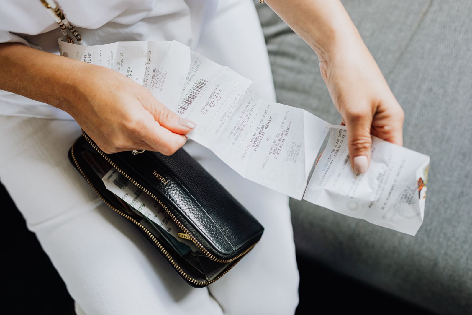 Manos sacando varios tickets de compra de una cartera negra