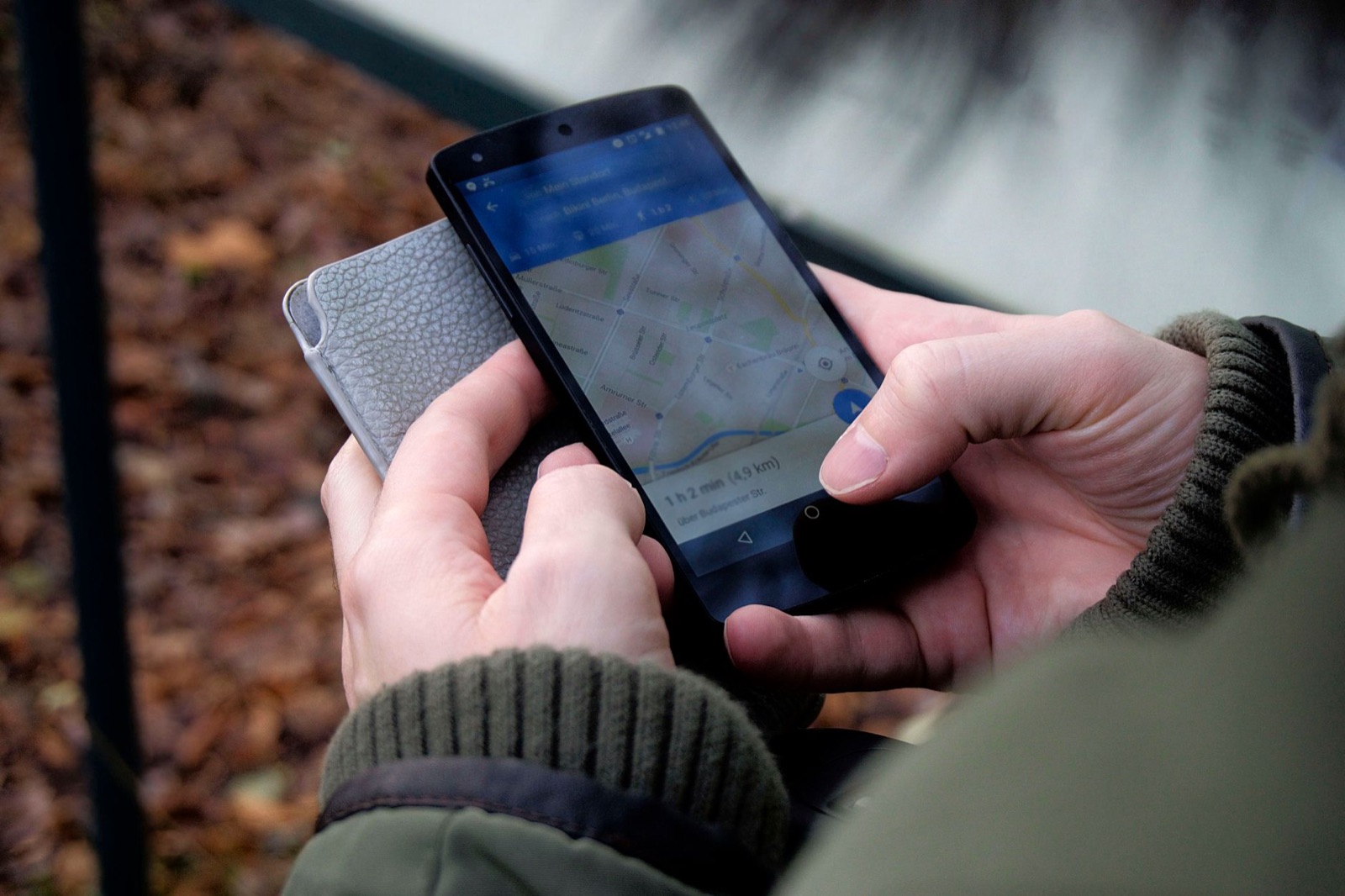 Manos sosteniendo un teléfono móvil con una aplicación de mapas abierta en la calle